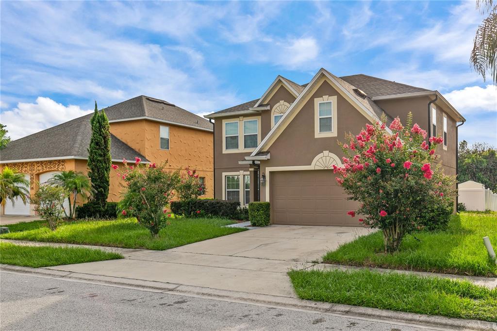 A two-story brown house with a garage and a front yard with flowering bushes — 8830 ISLA BELLA DRIVE, ORLANDO, FL