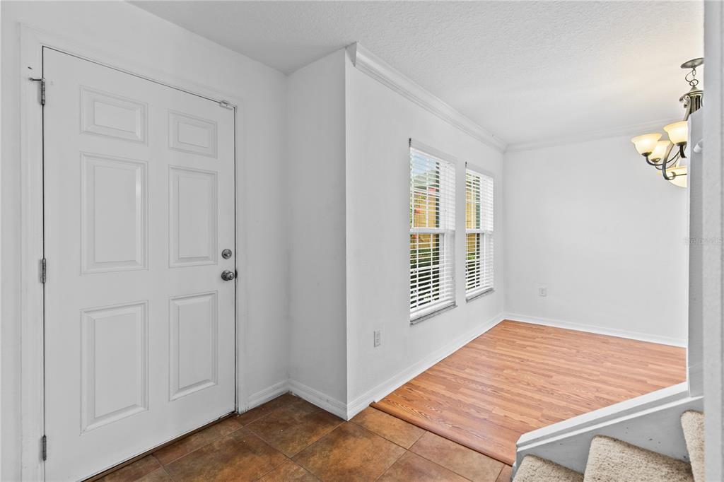An entryway with tiled flooring, a white front door, and an adjacent room with wood flooring — 8830 ISLA BELLA DRIVE, ORLANDO, FL