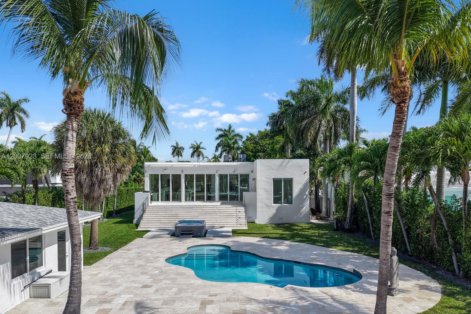 A white modern house features a swimming pool, hot tub, and palm trees in the backyard — 1090 NE 84th St, Miami FL 33138, MIAMI, FL