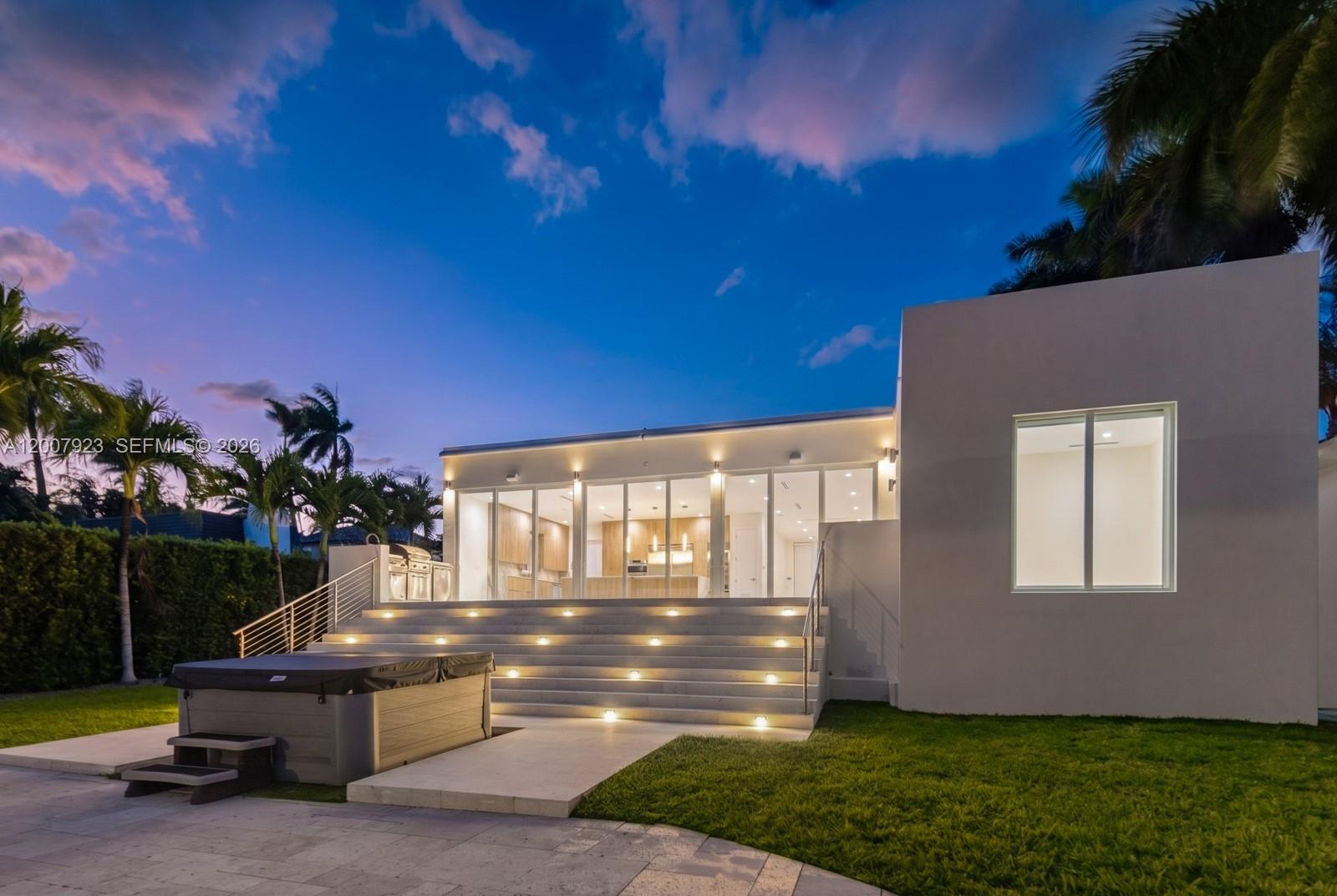 A modern house exterior features a hot tub, illuminated stone steps, and large glass doors — 1090 NE 84th St, Miami FL 33138, MIAMI, FL