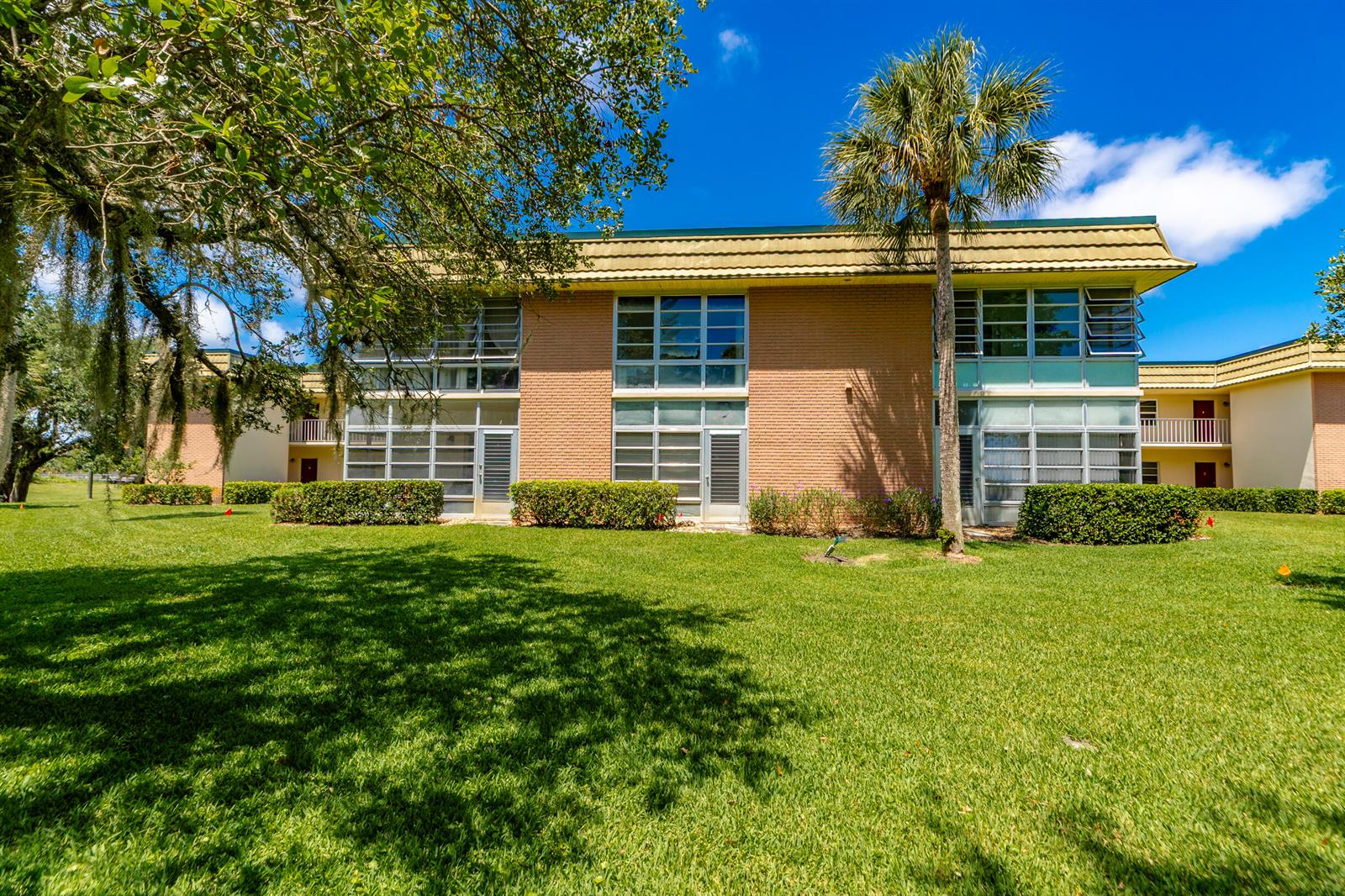 A two-story brick apartment building with large windows and a palm tree on the lawn — VERO BEACH, FL