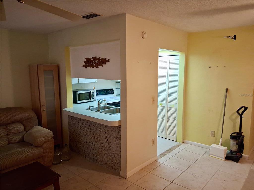 A living room with tile floors opens to a kitchen featuring a tiled breakfast bar — 1250 S PINELLAS AVENUE UNIT 511, TARPON SPRINGS, FL