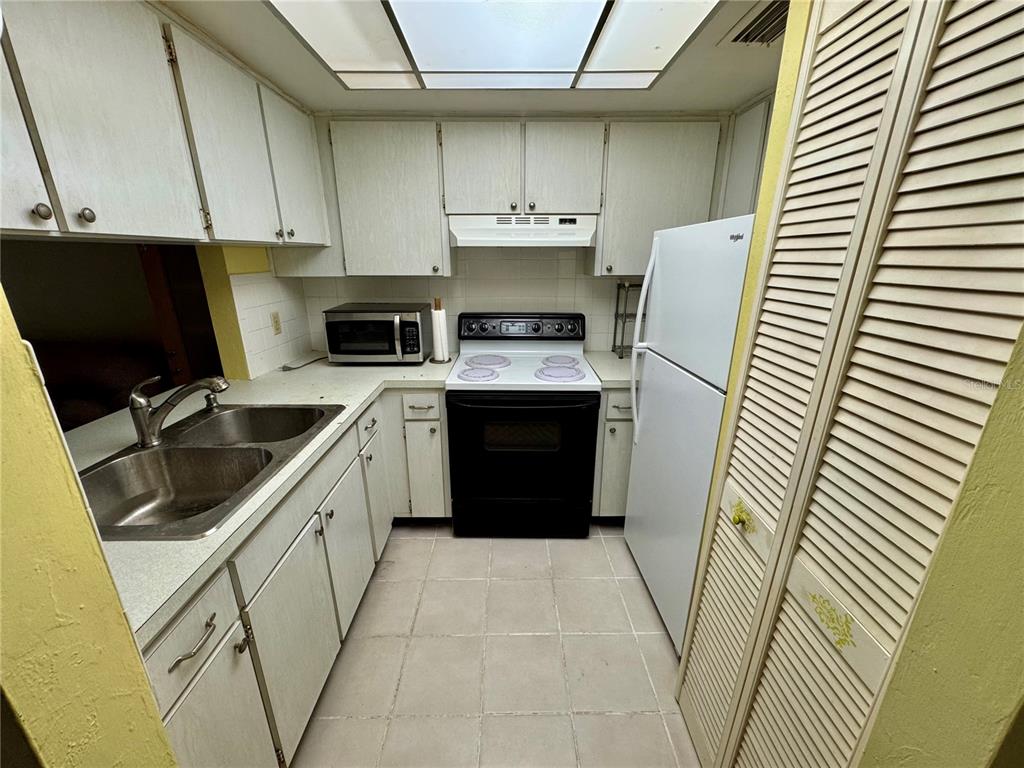A kitchen features white cabinets, a black stove, a white refrigerator, and tiled flooring — 1250 S PINELLAS AVENUE UNIT 511, TARPON SPRINGS, FL