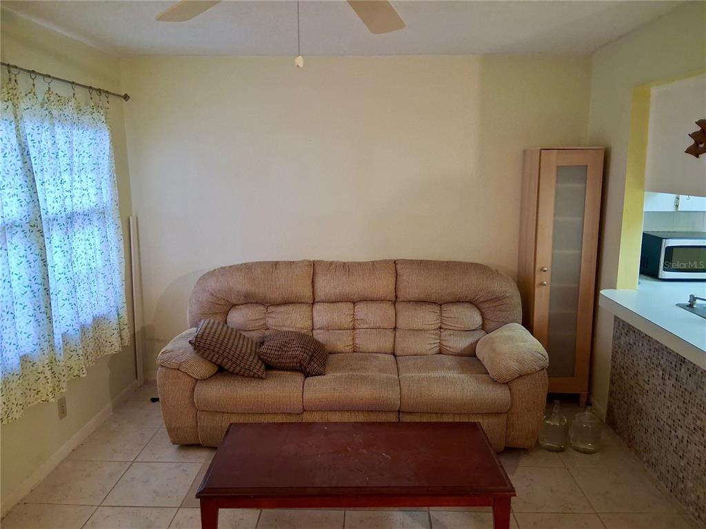 A living room features a beige sofa, a wooden coffee table, and tiled flooring — 1250 S PINELLAS AVENUE UNIT 511, TARPON SPRINGS, FL
