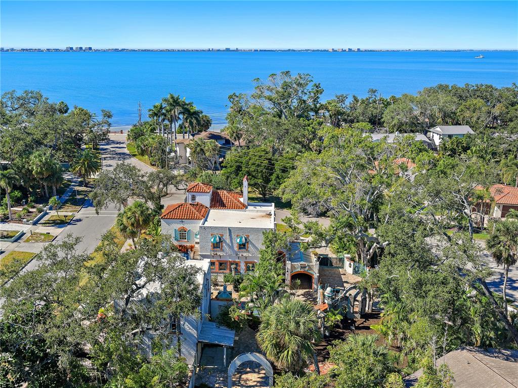 An aerial view shows a multi-story Mediterranean-style house surrounded by trees near the water — 2830 BAY SHORE CIRCLE, SARASOTA, FL
