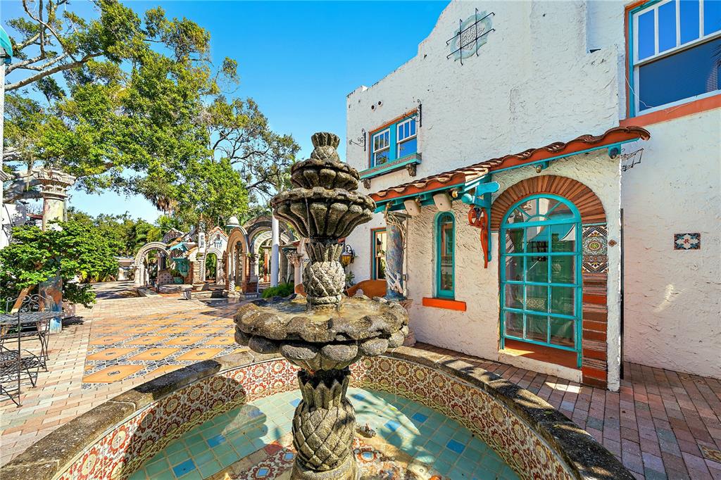 A stone fountain sits in a courtyard with decorative tile accents and a stucco building — 2830 BAY SHORE CIRCLE, SARASOTA, FL