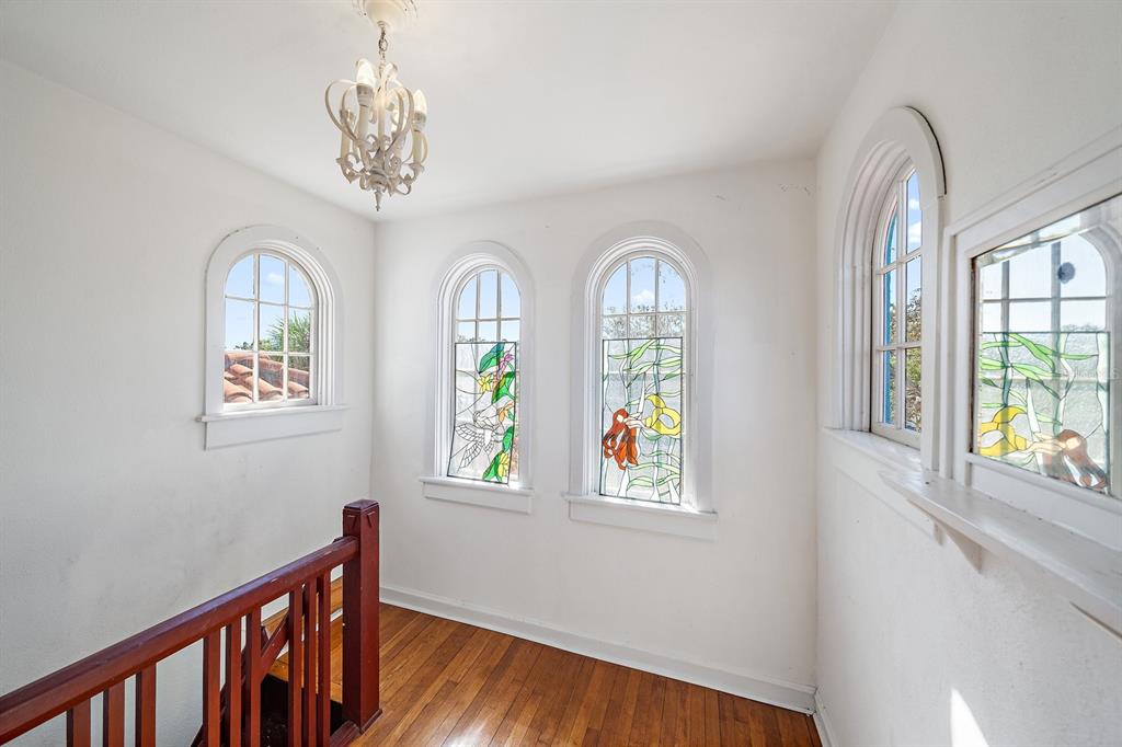 A landing with hardwood floors, a chandelier, and several arched windows with stained glass accents — 2830 BAY SHORE CIRCLE, SARASOTA, FL