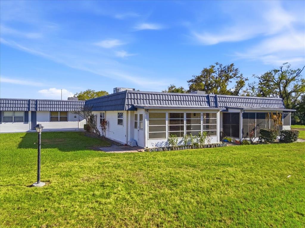 A single-story house with a blue mansard roof, white siding, and a screened-in porch — 205 ANDOVER PLACE N UNIT 119, SUN CITY CENTER, FL
