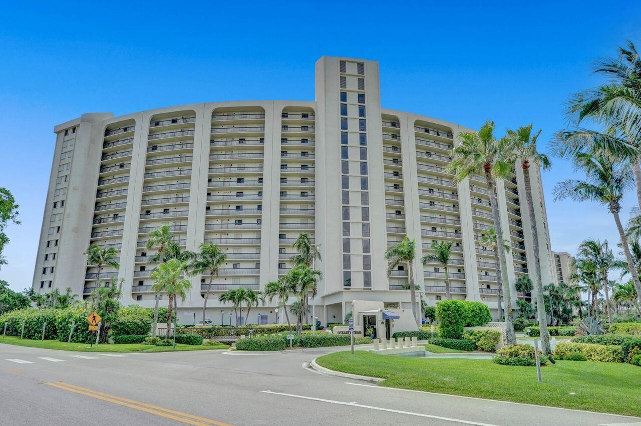 A multi-story beige residential building with balconies and palm trees sits behind a paved road — 400 Ocean Trail Way # 504, Jupiter FL 33477, JUPITER, FL