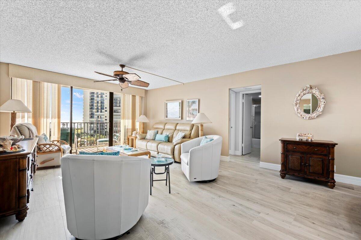A living room features light wood-look flooring, white armchairs, a beige sofa, and balcony access — 400 Ocean Trail Way # 504, Jupiter FL 33477, JUPITER, FL
