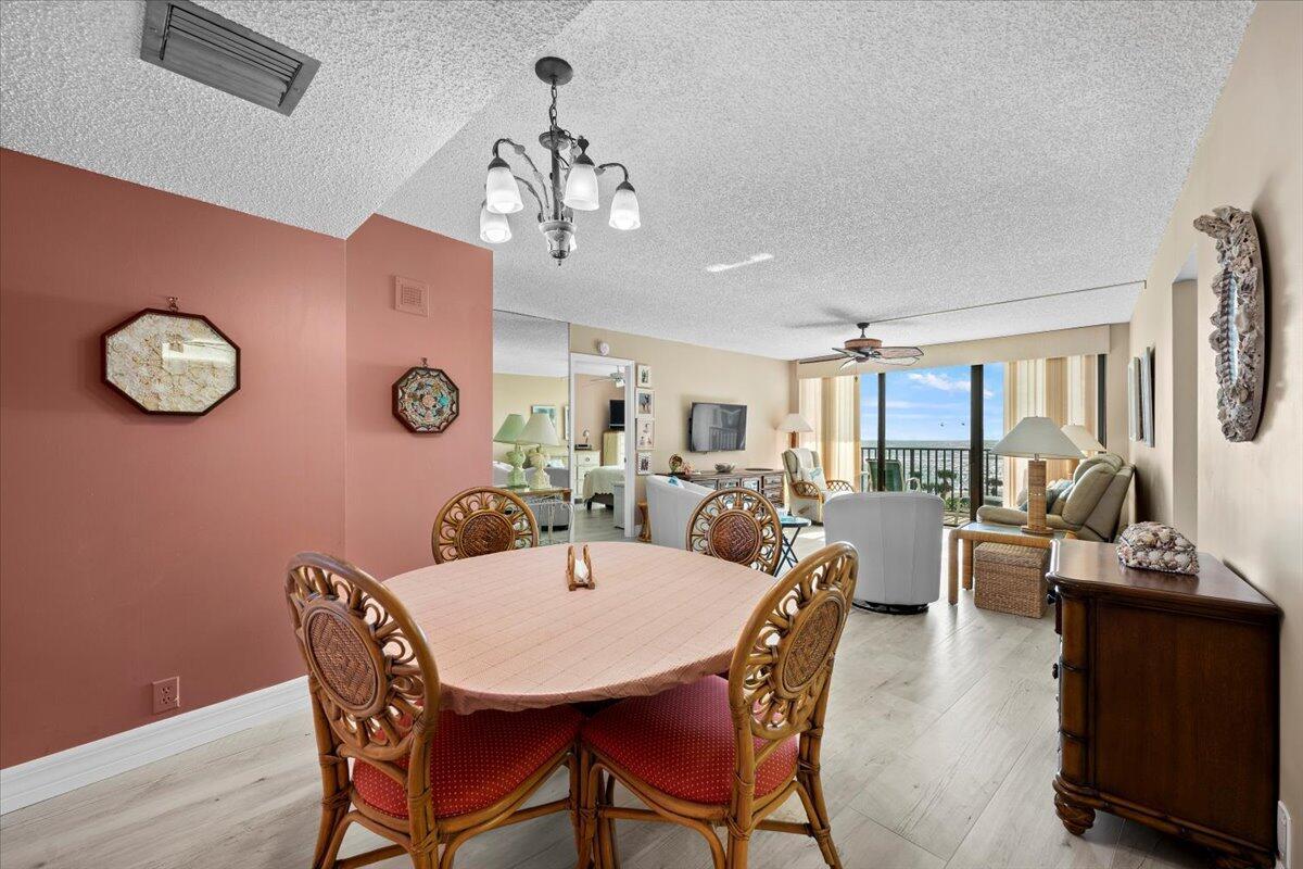 A dining area with a round table and rattan chairs opens into a bright living room — 400 Ocean Trail Way # 504, Jupiter FL 33477, JUPITER, FL