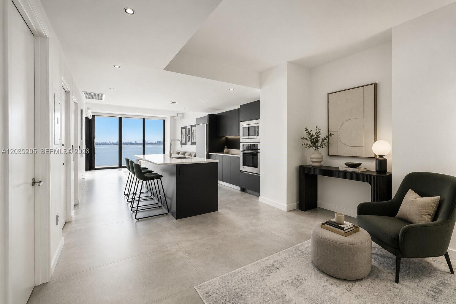 A modern kitchen with a dark island and stools overlooks a water view — 460 NE 28th St # 805, Miami FL 33137, MIAMI, FL