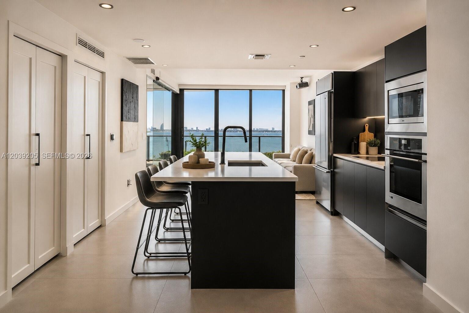 A modern kitchen features a central island with bar seating and views of the ocean — 460 NE 28th St # 805, Miami FL 33137, MIAMI, FL