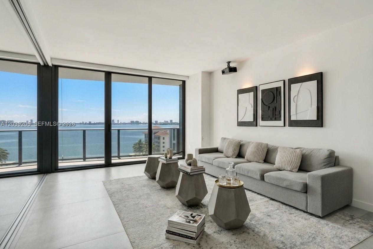 A modern living room features a gray sofa, geometric side tables, and floor-to-ceiling windows — 460 NE 28th St # 805, Miami FL 33137, MIAMI, FL