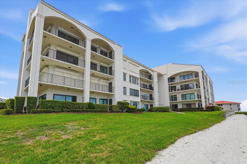 A multi-story white apartment building features arched balconies and a manicured lawn — 401 MARINER DRIVE UNIT 401, TARPON SPRINGS, FL