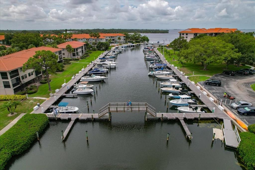An aerial view shows a narrow marina with docked boats between two residential buildings — 401 MARINER DRIVE UNIT 401, TARPON SPRINGS, FL