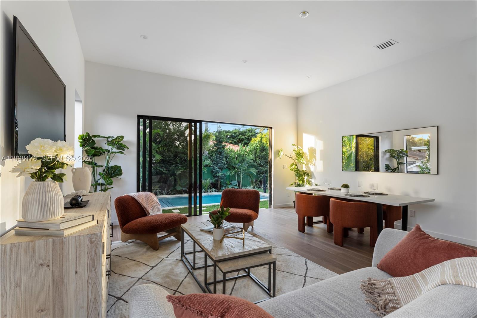 A modern living and dining area features a pool view through large sliding glass doors — 2434 SW 19th St, Miami FL 33145, MIAMI, FL