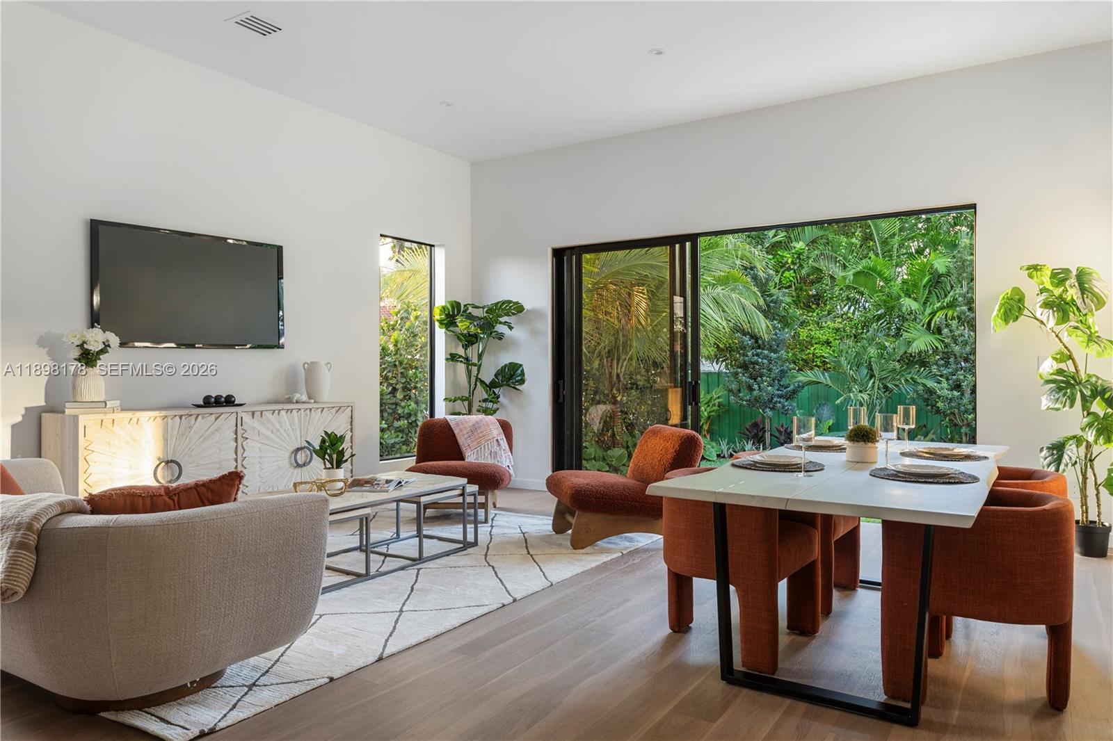 A modern living and dining area features white walls, wood floors, and large glass doors — 2434 SW 19th St, Miami FL 33145, MIAMI, FL