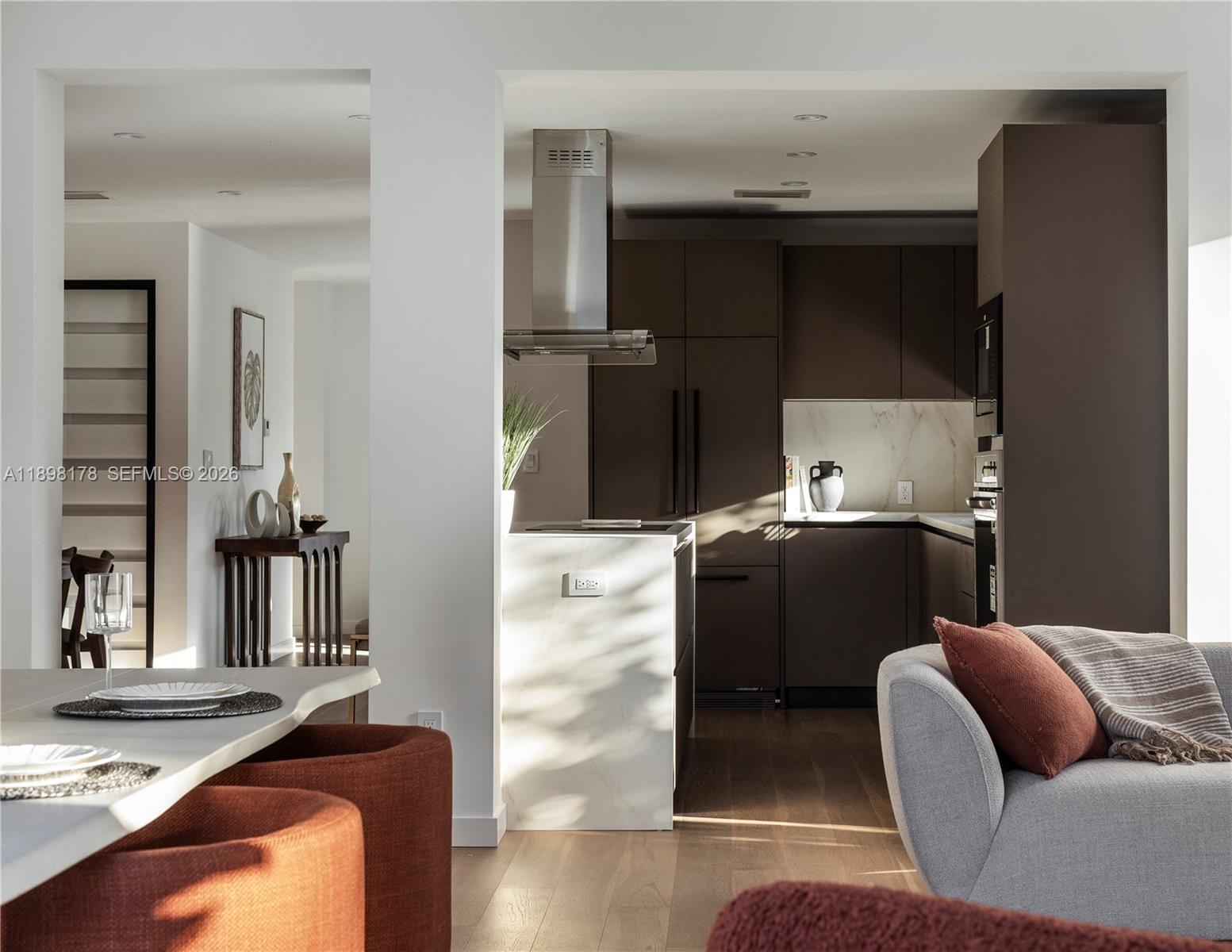 A modern kitchen features dark cabinetry, a marble-topped island, and an adjacent dining area — 2434 SW 19th St, Miami FL 33145, MIAMI, FL