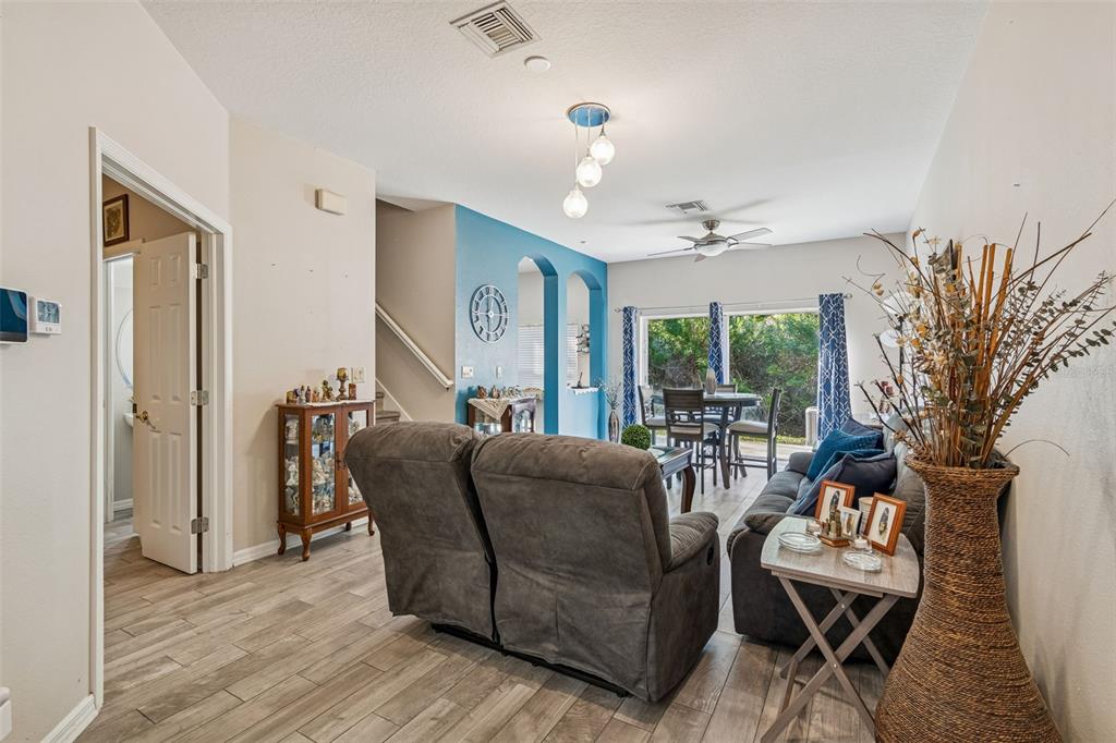 A living room with gray tile floors, a blue accent wall, and a dining area — 8809 CASABLANCA WAY, TAMPA, FL