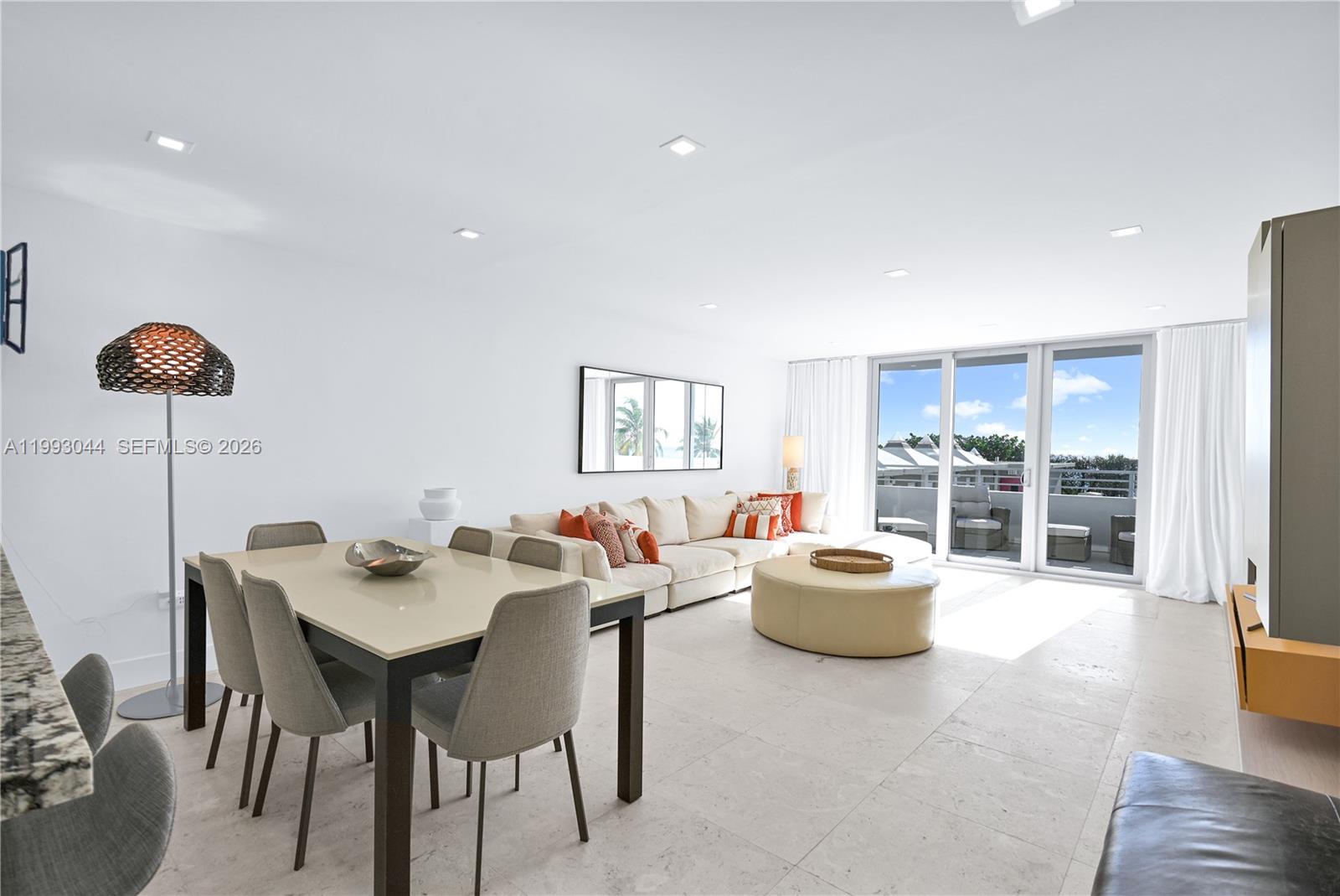 A bright living and dining area features white walls, tile floors, and a balcony view — 5555 Collins Ave # 3N, Miami Beach FL 33140, MIAMI BEACH, FL