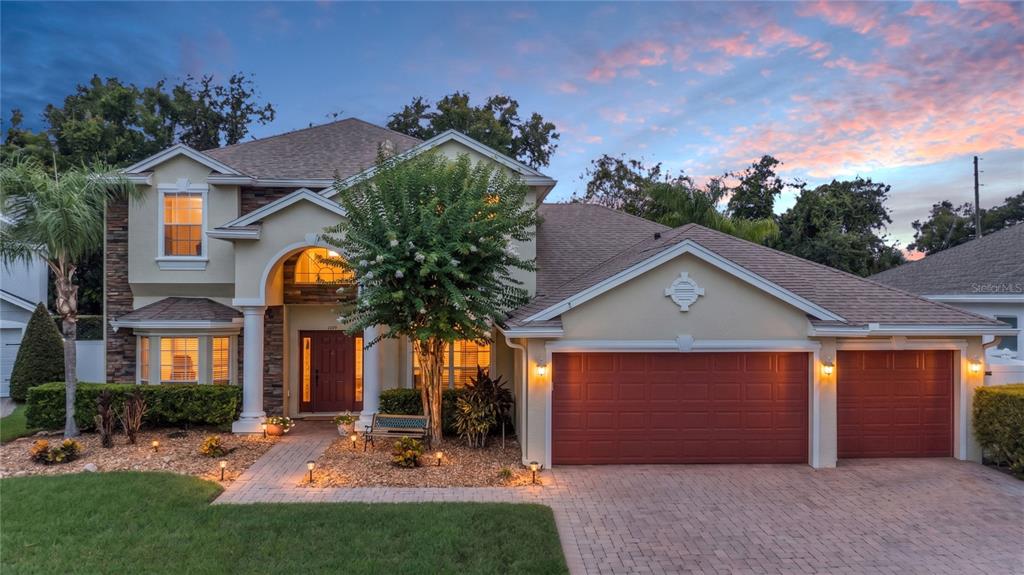 A two-story house with a stone facade, a three-car garage, and a paved walkway — 3342 HERRINGRIDGE DRIVE, ORLANDO, FL