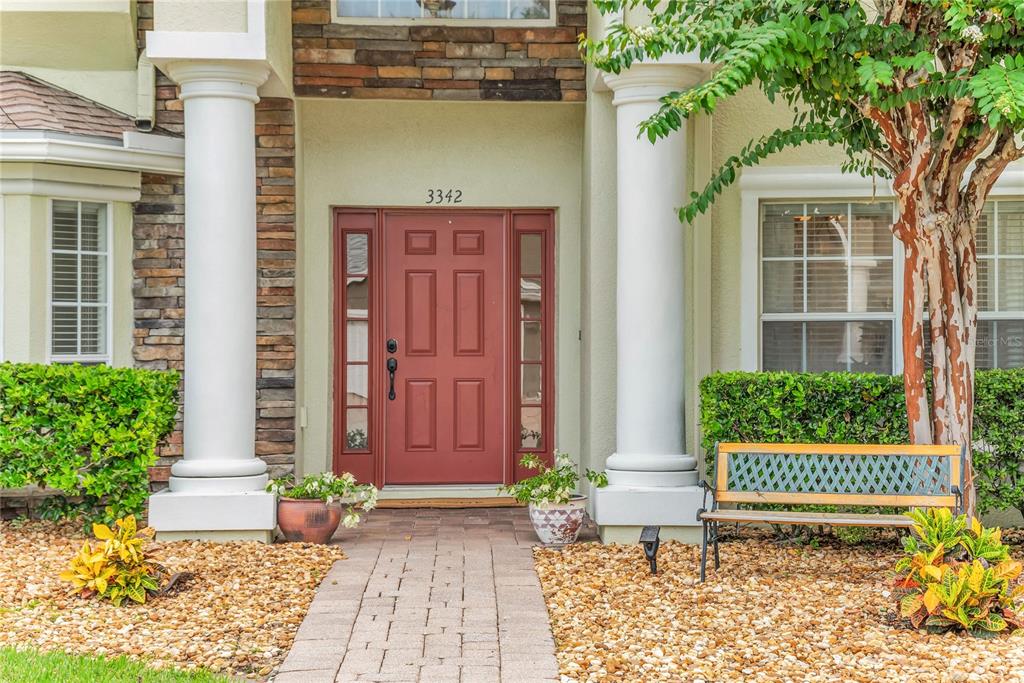 The front entrance features a red door with sidelights, stone accents, and two white columns — 3342 HERRINGRIDGE DRIVE, ORLANDO, FL