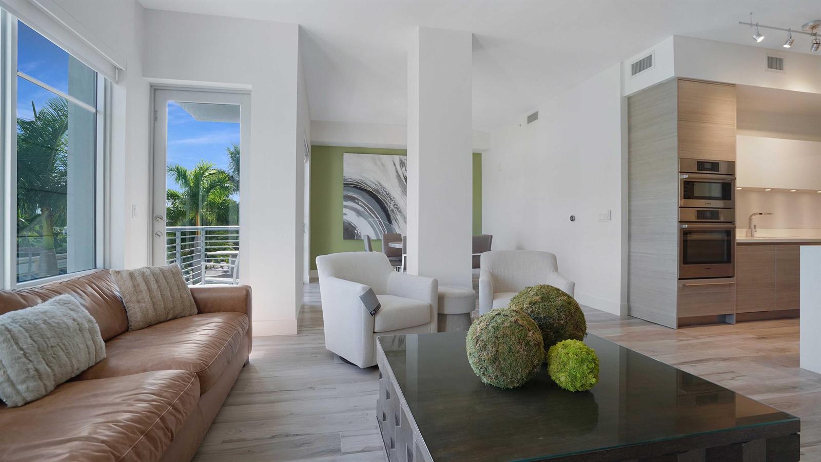 A modern living room features a leather sofa, two armchairs, and a view of palm trees — 155 E Boca Raton Road # 301, Boca Raton FL 33432, BOCA RATON, FL