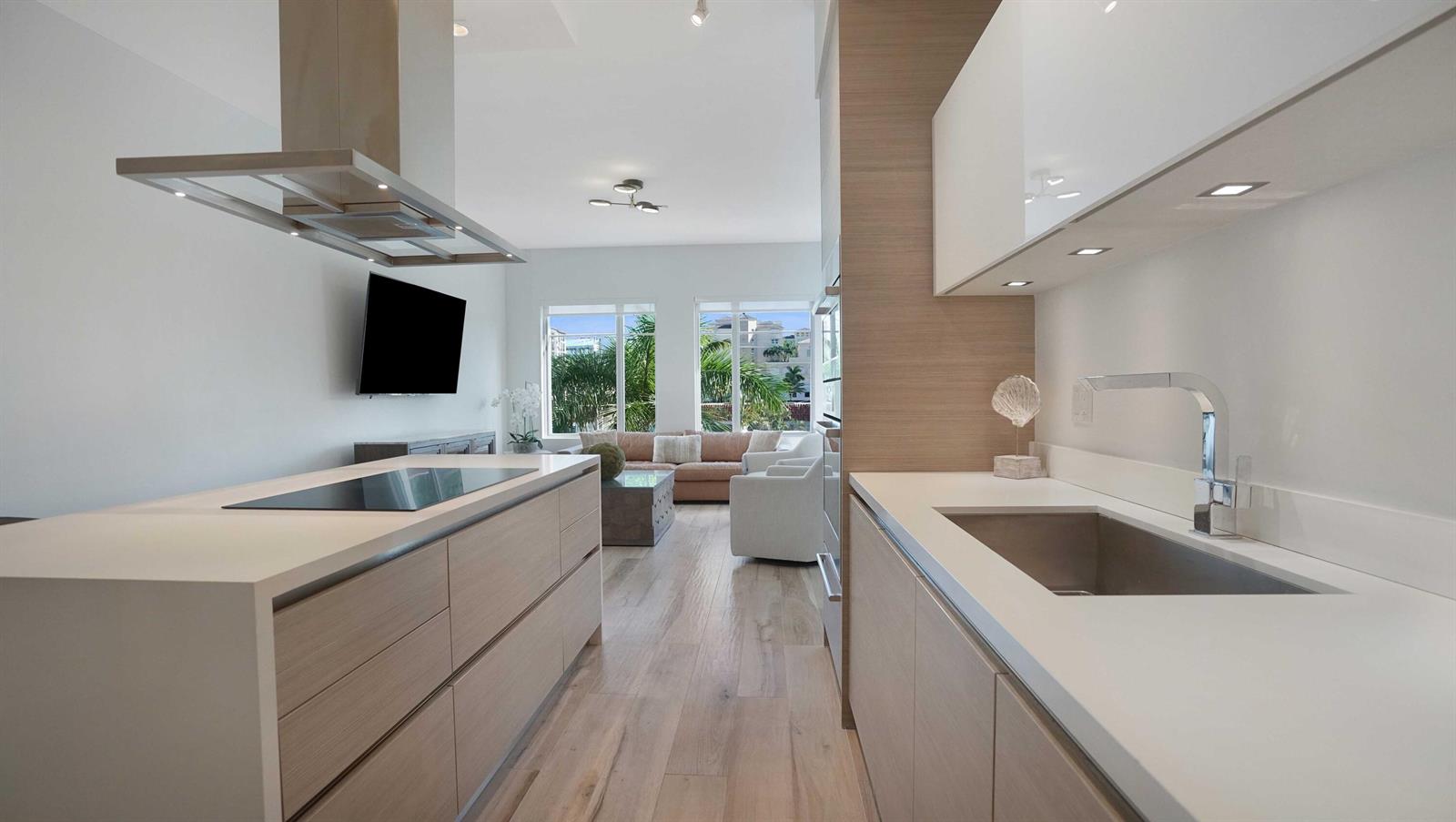 A modern kitchen with light wood cabinetry and white countertops opens into a living area — 155 E Boca Raton Road # 301, Boca Raton FL 33432, BOCA RATON, FL