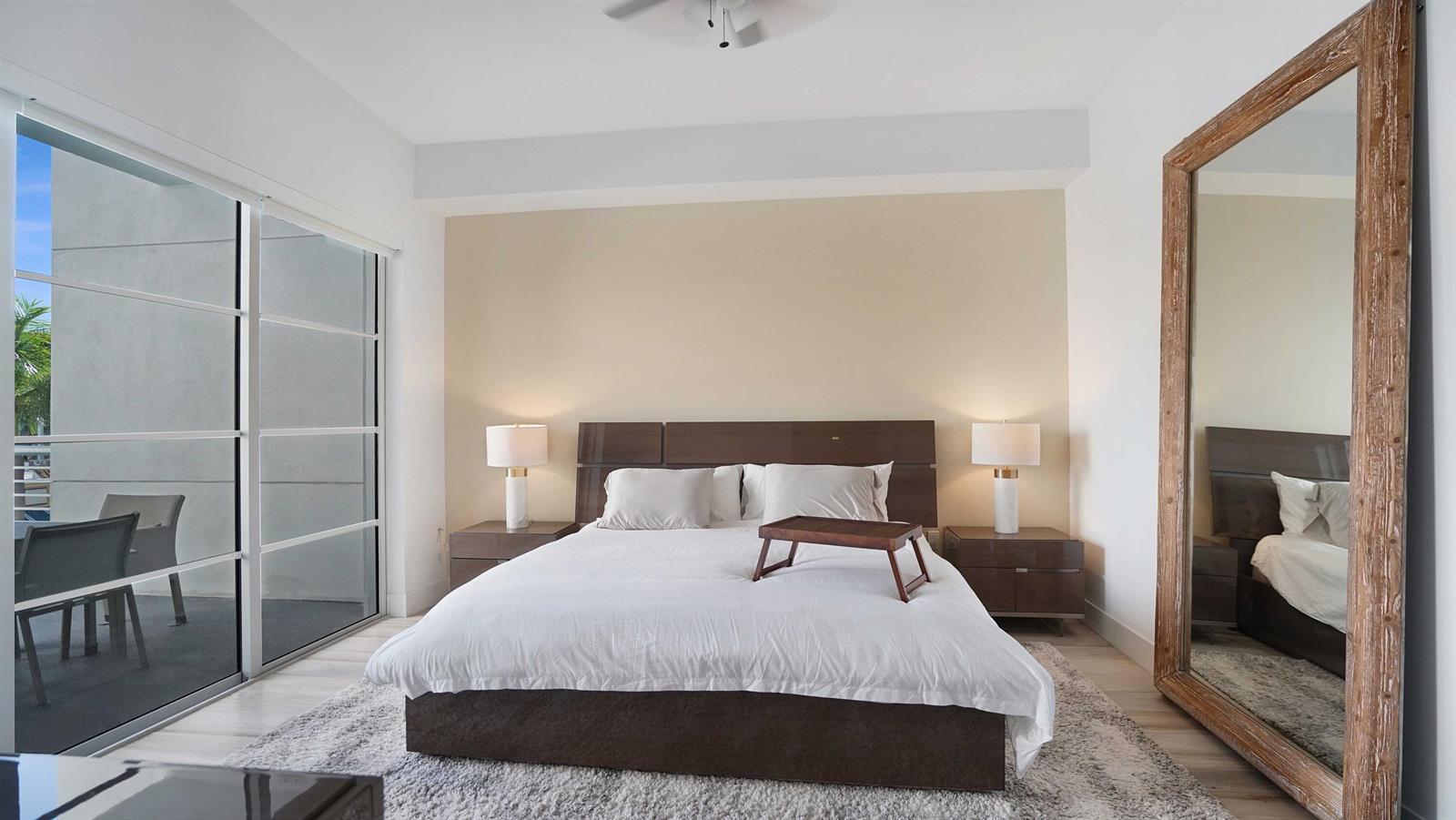 A bedroom features a bed with a breakfast tray, two nightstands, and a large mirror — 155 E Boca Raton Road # 301, Boca Raton FL 33432, BOCA RATON, FL