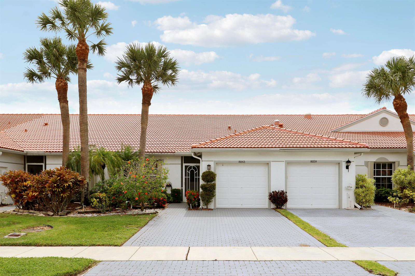 A single-story residential building with a tiled roof, two garage doors, and palm trees — 8063 Dolomtian Way, Boynton Beach FL 33472, BOYNTON BEACH, FL