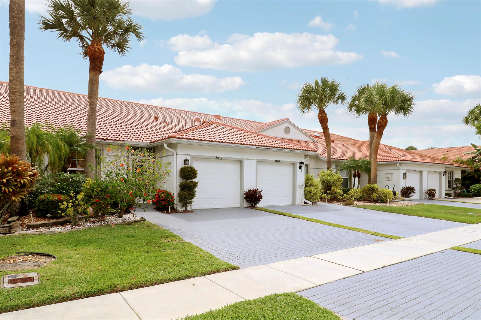 A row of single-story townhomes with red tile roofs and paved driveways under a blue sky — 8063 Dolomtian Way, Boynton Beach FL 33472, BOYNTON BEACH, FL