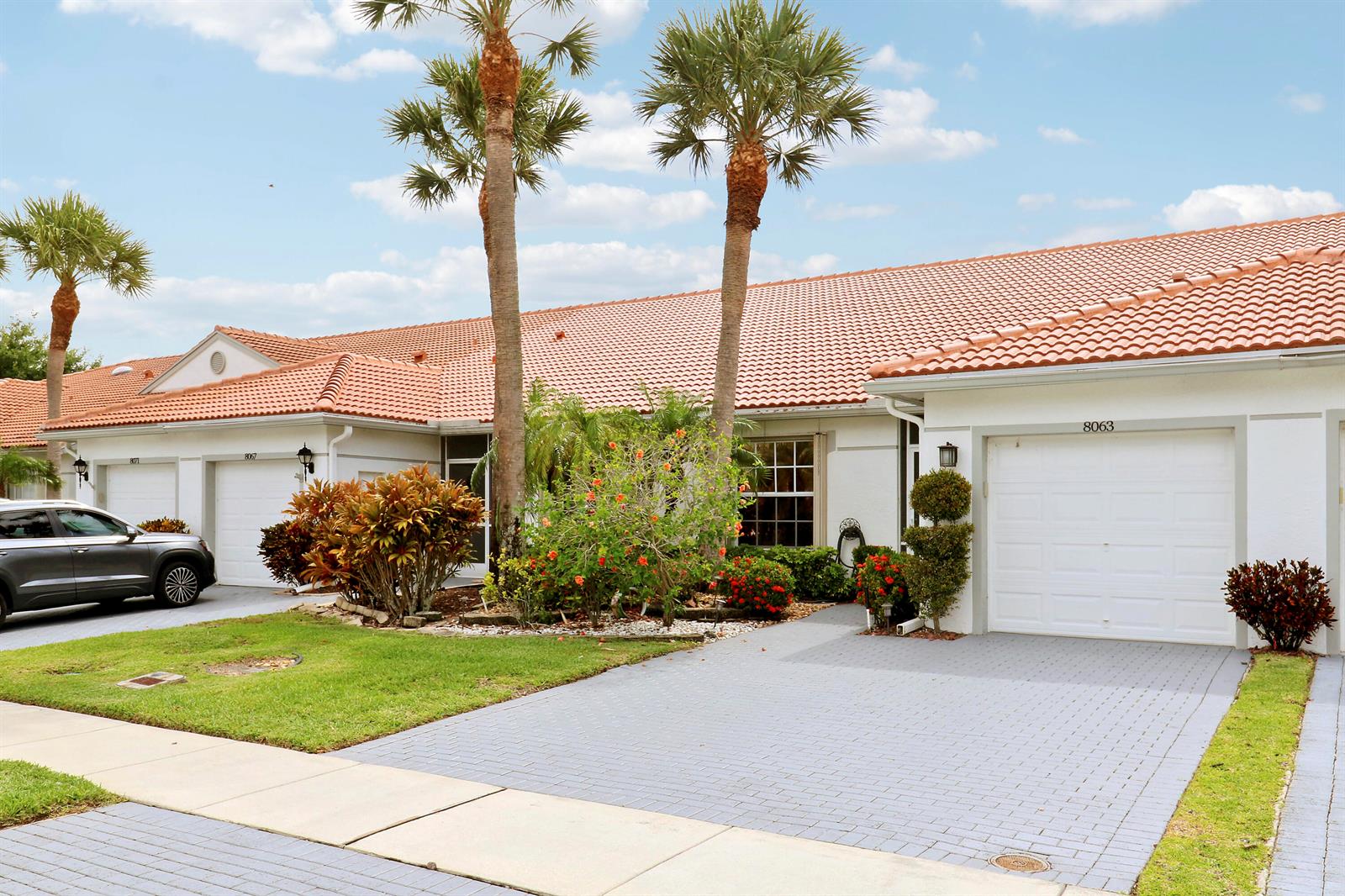 A single-story residential building with a tiled roof, palm trees, and paved driveways — 8063 Dolomtian Way, Boynton Beach FL 33472, BOYNTON BEACH, FL