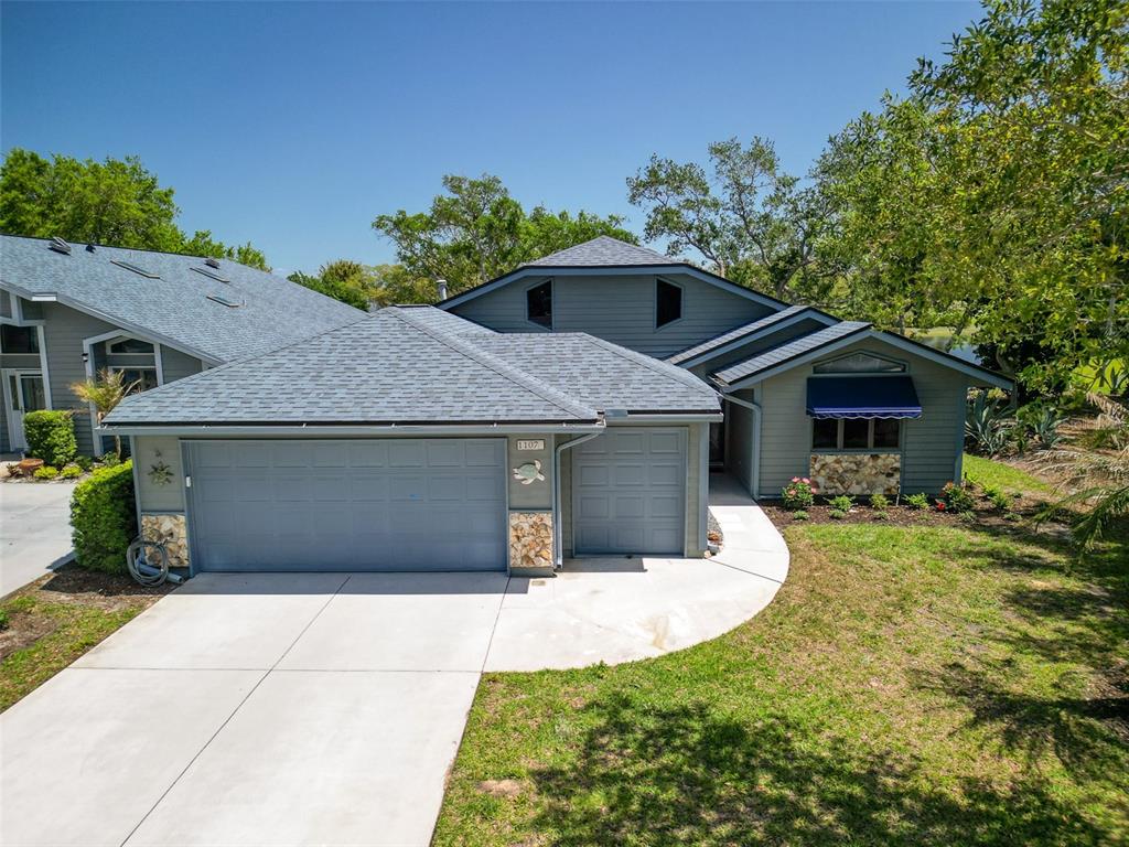 An exterior view of a gray house with a two-car garage and a shingled roof — 1107 LOCH LOMOND COURT, NEW SMYRNA BEACH, FL