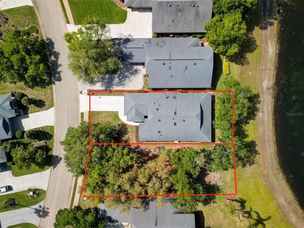 An aerial view shows a house with a gray roof and a wooded backyard — 1107 LOCH LOMOND COURT, NEW SMYRNA BEACH, FL