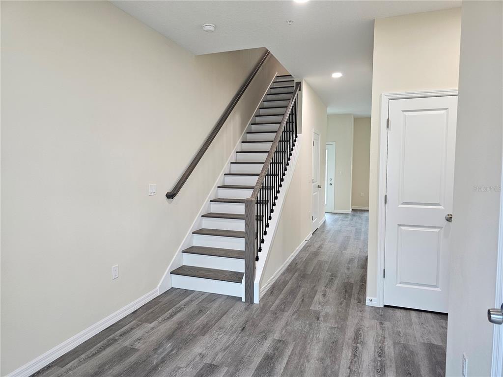 An interior view shows a staircase with dark wood treads and a white hallway — 4371 CAMBIO GARDENS COURT, TAMPA, FL