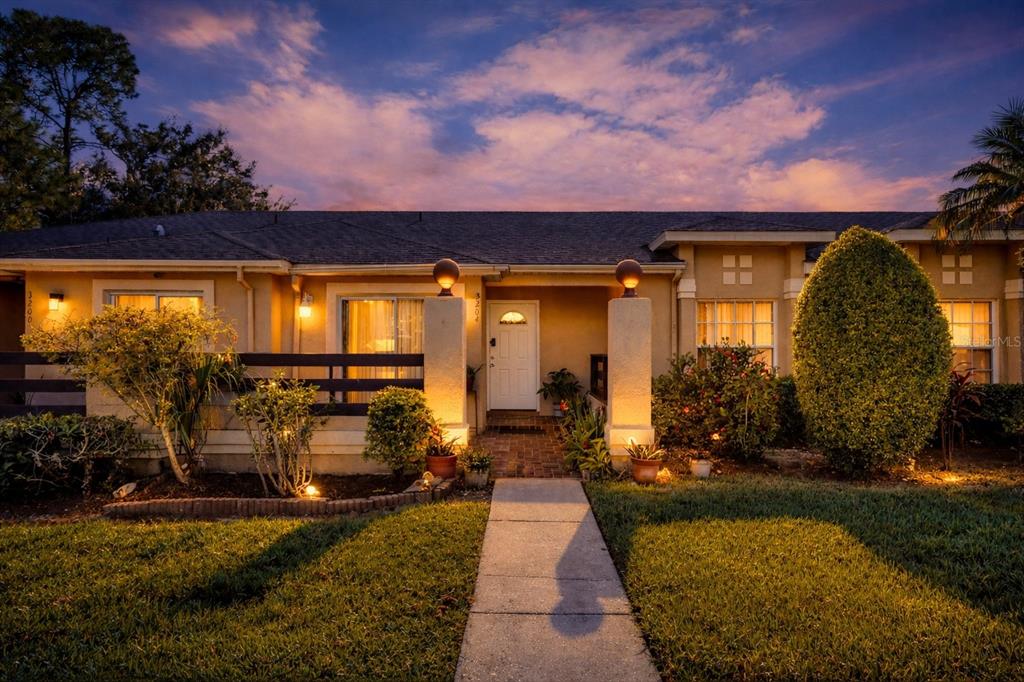 A single-story house exterior at dusk with a paved walkway leading to the front entrance — 3204 TIDEWATER DRIVE, KISSIMMEE, FL