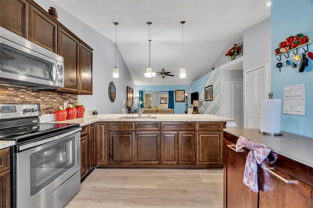 A kitchen with dark wood cabinets, stainless steel appliances, and a granite-topped island — 3204 TIDEWATER DRIVE, KISSIMMEE, FL