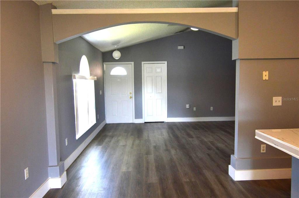 An interior view shows a room with gray walls, wood-look flooring, and an arched entryway — 424 DELICATA DRIVE, ORLANDO, FL