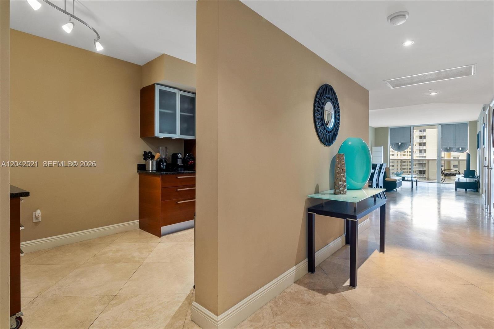 A hallway with a console table leads to a living area with floor-to-ceiling windows — 1800 S Ocean Dr # 608, Hallandale Beach FL 33009, HALLANDALE BEACH, FL