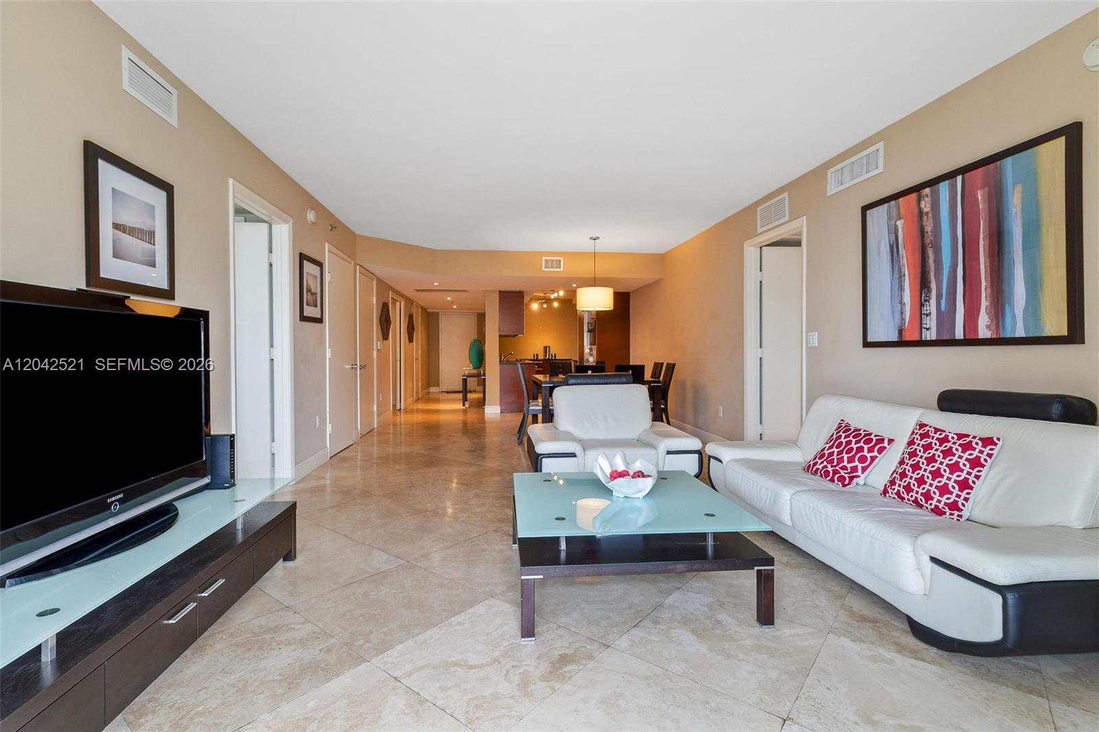 A living room features tile floors, a white sofa, a glass coffee table, and television — 1800 S Ocean Dr # 608, Hallandale Beach FL 33009, HALLANDALE BEACH, FL