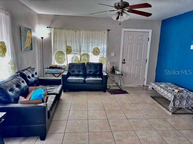 A living room features black leather sofas, tile flooring, a ceiling fan, and blue walls — 1907 E EMMA STREET, TAMPA, FL