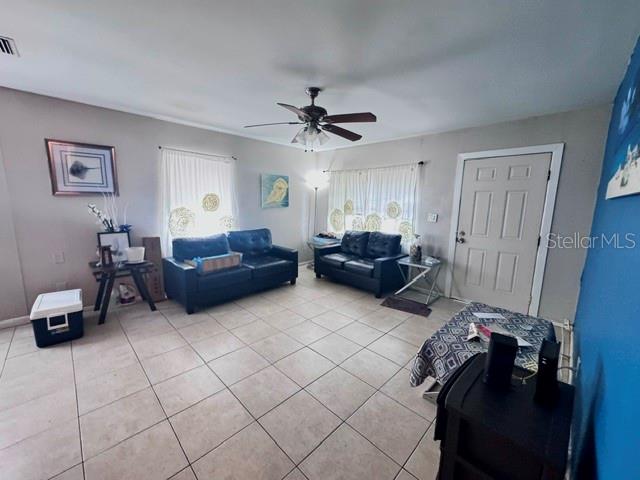 A living room features tile flooring, two black sofas, a ceiling fan, and a door — 1907 E EMMA STREET, TAMPA, FL