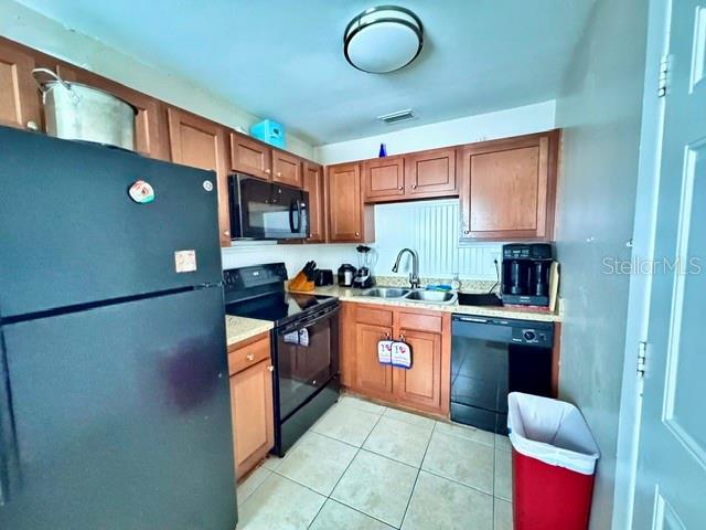 A kitchen features wooden cabinets, a black refrigerator, a stove, and a dishwasher — 1907 E EMMA STREET, TAMPA, FL