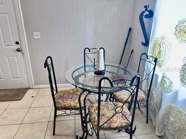 A small round glass dining table with four floral-patterned metal chairs sits on tiled flooring — 1907 E EMMA STREET, TAMPA, FL
