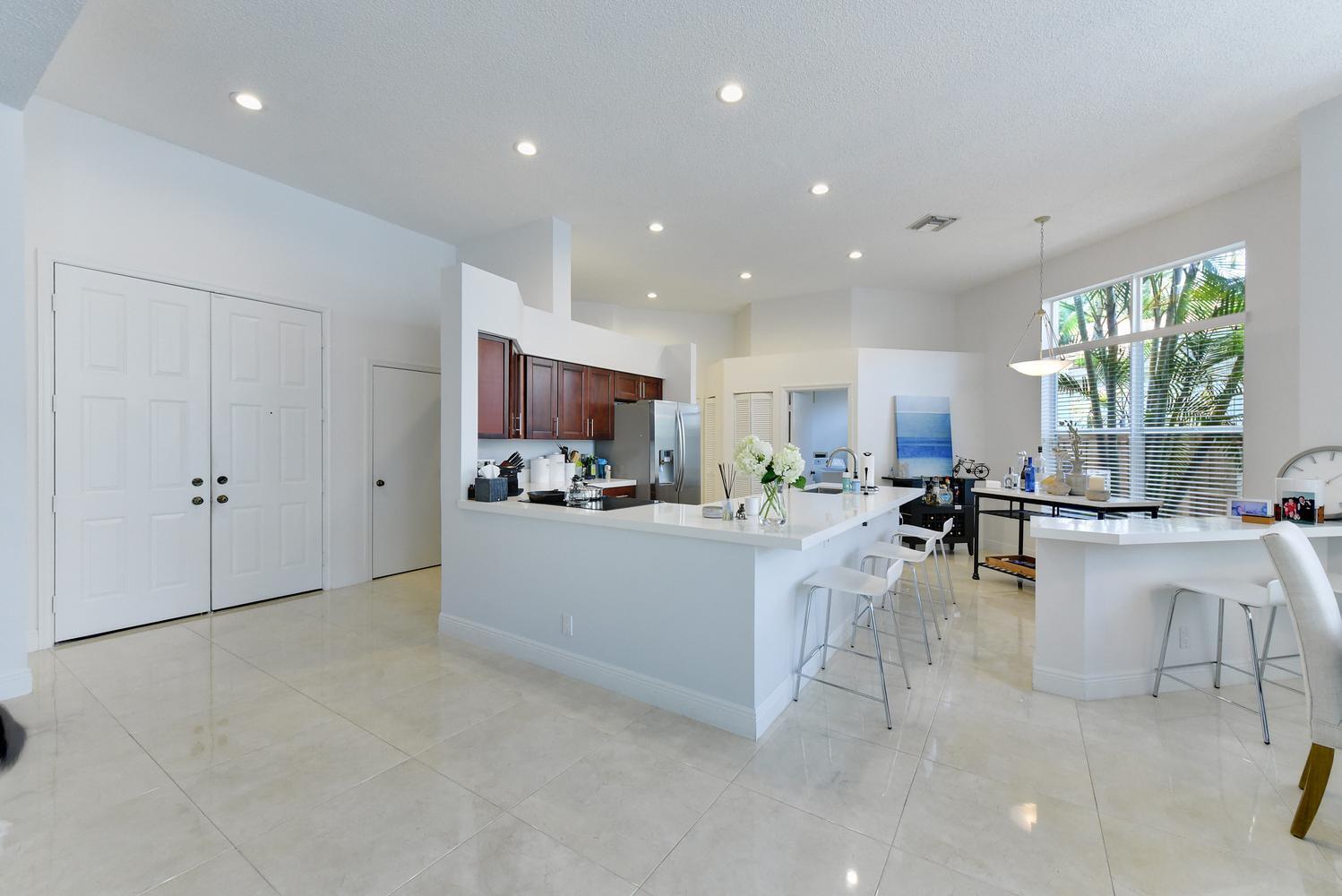 A bright kitchen features white countertops, dark wood cabinets, and light tile flooring — 6685 NW 24th Terrace, Boca Raton FL 33496, BOCA RATON, FL
