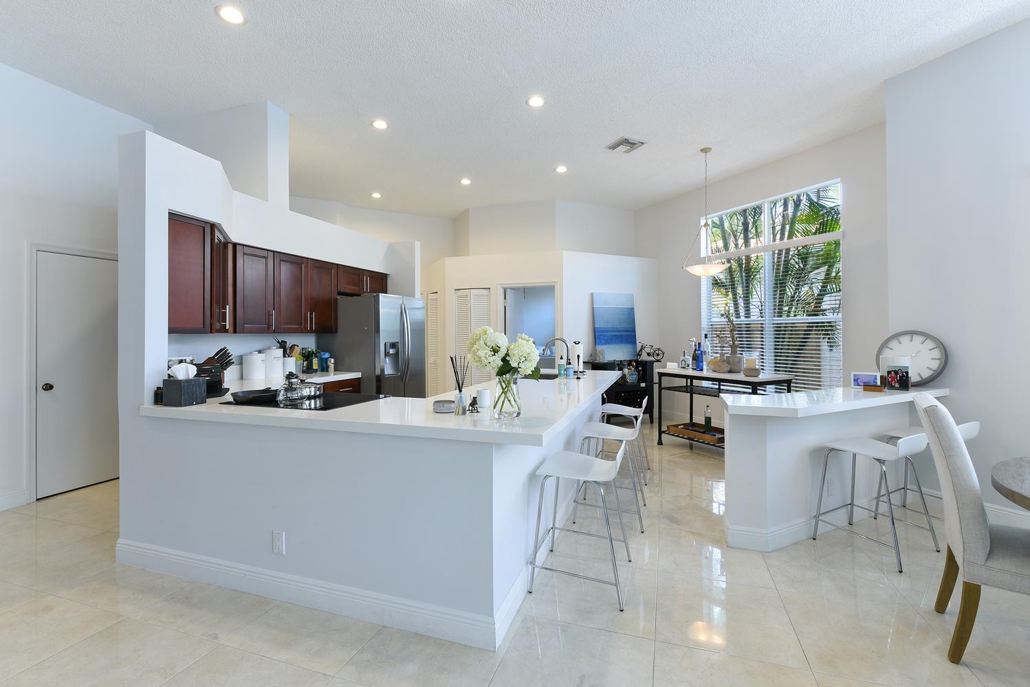 A kitchen with dark wood cabinets, white countertops, a breakfast bar, and tile flooring — 6685 NW 24th Terrace, Boca Raton FL 33496, BOCA RATON, FL