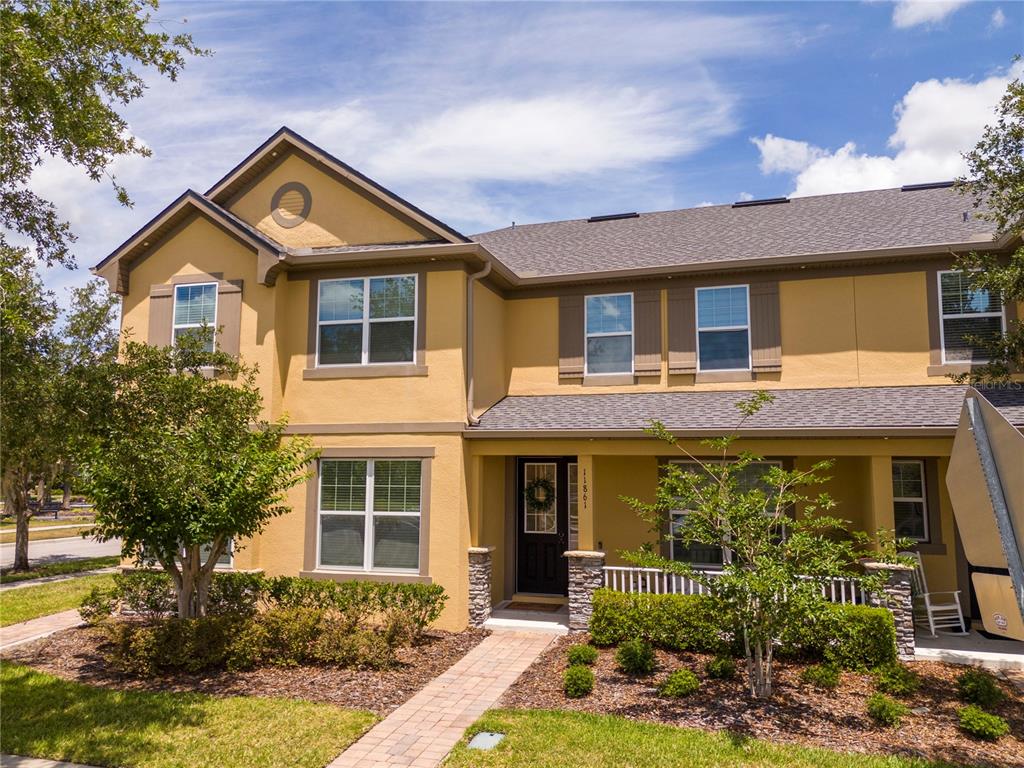 A two-story yellow townhouse with a covered front porch and a brick walkway — 11861 VERMILLION AVENUE, WINDERMERE, FL