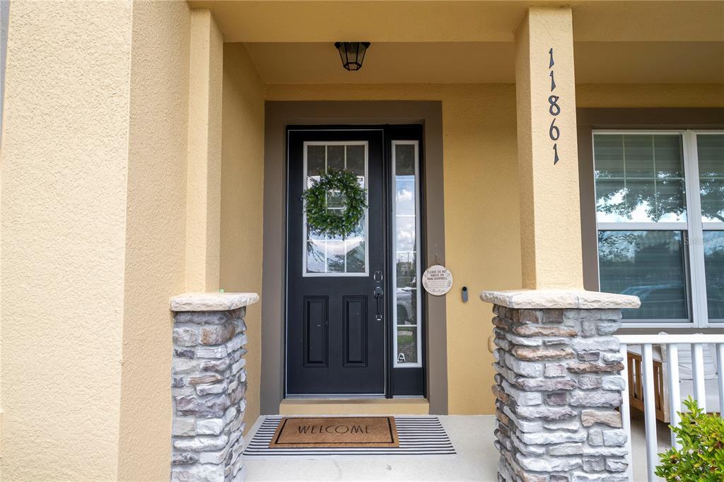The front entrance features a dark door with a wreath, stone pillars, and a welcome mat — 11861 VERMILLION AVENUE, WINDERMERE, FL