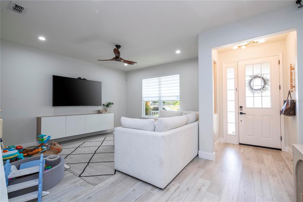 A living room features a white sofa, a wall-mounted television, and a front entryway — 11861 VERMILLION AVENUE, WINDERMERE, FL